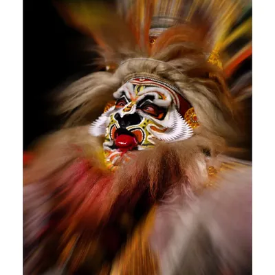 A dynamic, zoom-burst photograph of a Kathakali performer, creating a sense of intense motion and focusing on the powerful facial expression. This is an example of my creative event photography.