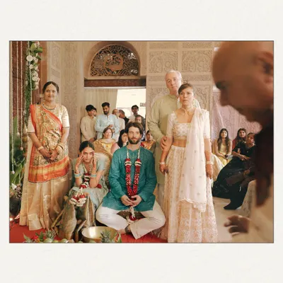 A temple wedding, captured with a documentary feel. This wide shot shows the couple amidst their family during the ceremony, giving a sense of the sacred space and the community witnessing their union. The perspective from behind a priest adds a layer of authenticity.