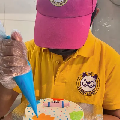 Our baker adds the finishing touches to a colorful Holi cake. We use pet-safe, natural colors to create a festive treat that's as safe as it is fun.