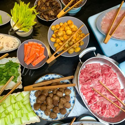 An abundant spread of fresh ingredients for our interactive hot-pot station. Guests can choose from thinly sliced meats, seafood, meatballs, and a variety of crisp vegetables to cook in their simmering broth.