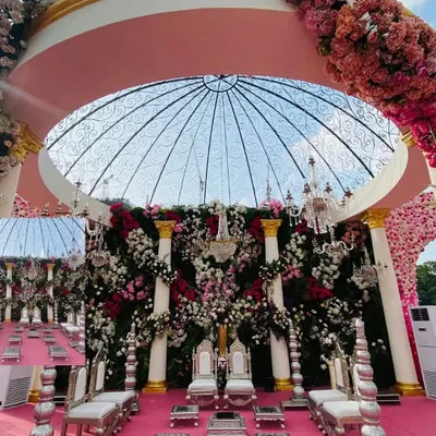 For this spectacular wedding, I designed a mandap that was a true floral masterpiece. A transparent dome structure is adorned with a dense canopy of pink, white, and red flowers, creating a heavenly space for the ceremony. The silver traditional seating adds a touch of regal elegance.