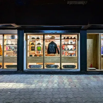 The completed facade of Capsul at night, fully illuminated. The design creates a series of glowing vitrines, turning the storefront into a beacon in the neighborhood and showcasing the products within like gallery pieces.