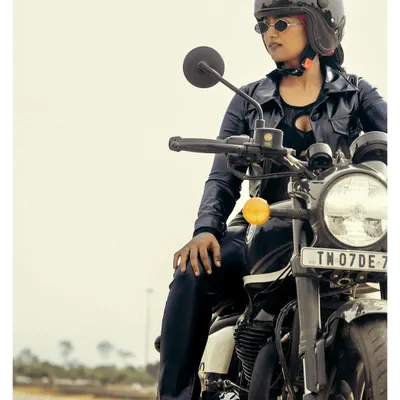 A cinematic shot of a model in a leather jacket and helmet, seated on a Royal Enfield motorcycle. This image captures a spirit of freedom and rebellion, perfect for an automotive or lifestyle brand campaign.