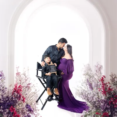 A beautiful family portrait celebrating the upcoming arrival. We captured this sweet moment with the parents and their son, who is proudly holding a sign. The coordinated purple and black outfits and the floral arch create a picture-perfect memory.