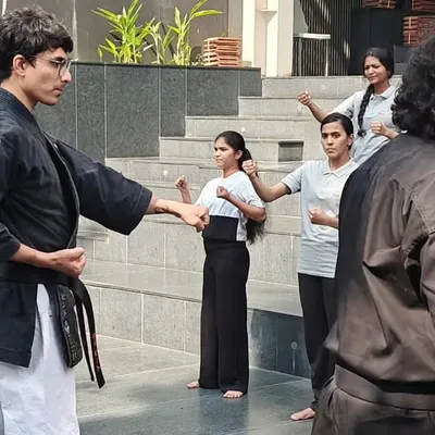 An instructor demonstrates a blocking technique during a self-defense workshop for female students at ISBR Business School in Bengaluru. The focus is on clear, step-by-step instruction.