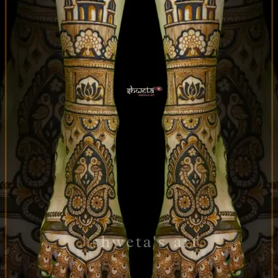 A regal leg mehendi design featuring architectural domes and intricate paisley peacock motifs. This pattern creates a stunningly symmetrical and grand look for the bride's feet.
