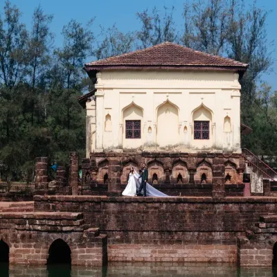 A destination wedding portrait in Goa, using the unique architecture of a historic temple and water tank to create a stunning, wide-angle shot.