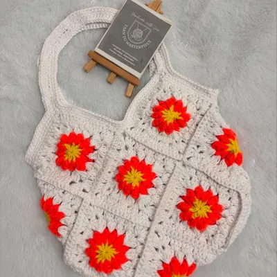 This shoulder bag is made from white granny squares, each featuring a vibrant sunflower design. It's a cheerful and stylish accessory, perfect for adding a pop of color to your look.
