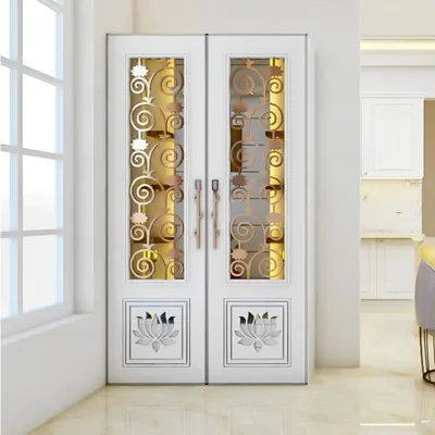 A set of beautiful double doors designed for a pooja room. The white frame is complemented by glass panels featuring golden metalwork in a swirling floral pattern and etched lotus motifs at the bottom. These doors are a statement piece that elevates the spiritual significance of the room.