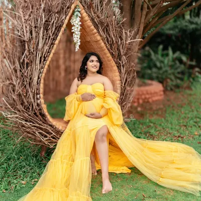 A radiant mom-to-be enjoying a beautiful day outdoors. This nest-like chair and the vibrant yellow gown create a stunning, bohemian-inspired look for a garden maternity shoot.