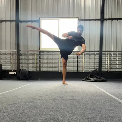 A student holds a perfect side kick, demonstrating excellent balance, flexibility, and control. This is a fundamental kick in many martial arts.