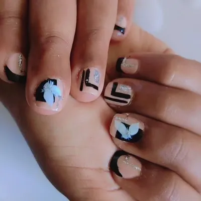 A close-up of a custom toe nail art design I created. It features a nude base with bold black geometric lines, delicate 3D white flower appliqués, and a touch of silver glitter for a modern, artistic finish.