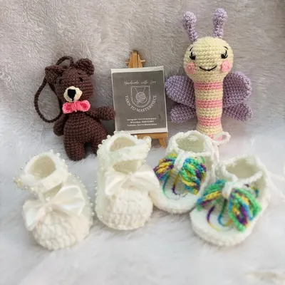 This custom gift hamper is full of variety, featuring two pairs of booties, a butterfly rattle, and a small bear keychain, offering a wonderful collection of handmade treasures.