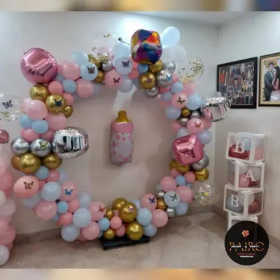 A beautiful ring decoration for a birthday party. This setup features a mix of pink, blue, gold, and silver balloons, with "BABY" blocks and butterfly accents.