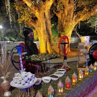 Our luxurious Arabian Paan Station set up under a beautifully lit tree. A costumed hostess, decorative hookahs, and an array of paan ingredients create an authentic and upscale vibe.