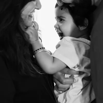 This intimate black and white close up captures a beautiful, raw moment between parents and their child. Without color, the focus is entirely on the expressions of love and laughter.