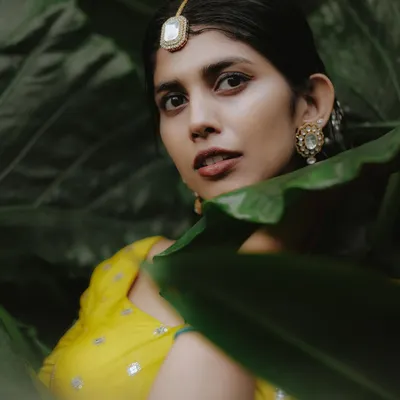 A stunning Haldi portrait of the bride, her bright yellow lehenga contrasting beautifully with the lush green leaves. This is how we make art out of tradition.