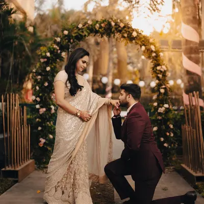 The classic proposal pose during an engagement ceremony, set against a beautiful floral arch. We capture these iconic moments with a soft, romantic feel.