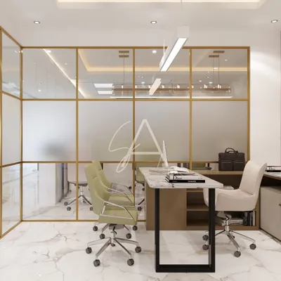 This office cabin features floor-to-ceiling glass partitions with a frosted lower half, balancing transparency and privacy. The gold-finished frames and marble flooring create a look of modern luxury, while the layout remains open and collaborative.