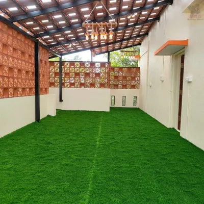 A finished terrace featuring a lush, green artificial lawn. This is a practical, no-maintenance solution for adding greenery to urban spaces like balconies and rooftops, paired here with a terracotta jali wall.
