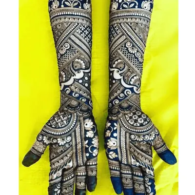 This is a perfect example of a negative space design, where the dark henna makes the skin's floral patterns pop. The bold, dark fingertips complete this modern and striking bridal look.