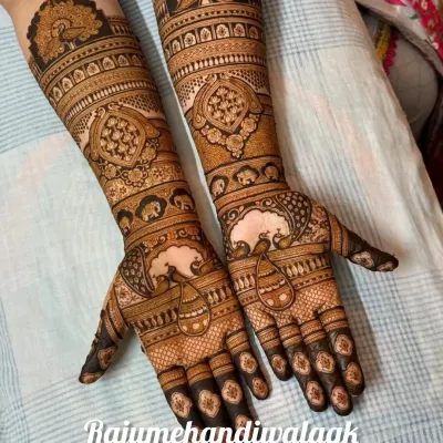 A classic full-arm bridal mehendi. This design is filled with traditional motifs like peacocks and architectural 'jharokhas', with very fine and detailed line work.