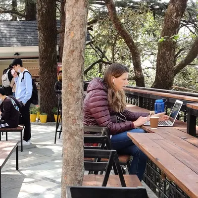 A student finds a quiet spot to work at the community hub we designed for Woodstock School. The flexible urban furniture, made from upcycled wooden decks, allows for various uses, from solo study to group gatherings.