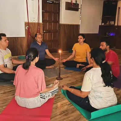 Tratak meditation, or steady gazing at a candle flame, is a powerful practice for calming the mind. Here, a group sits in a circle, sharing a moment of collective stillness and focus.