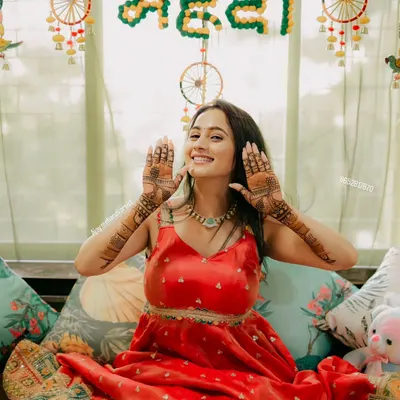 A happy client at her mehndi ceremony, smiling and showing her beautiful henna designs.