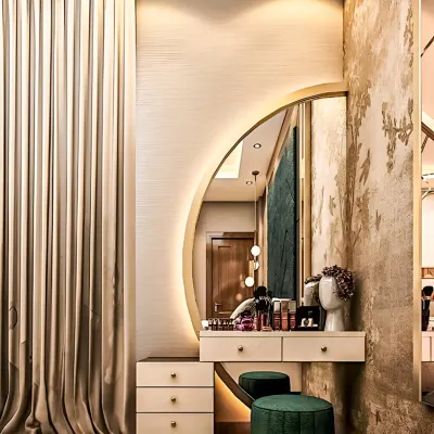 An elegant dressing table with a large, backlit semi-circular mirror. The design includes drawers for storage and is paired with plush green stools, creating a glamorous and functional vanity corner.