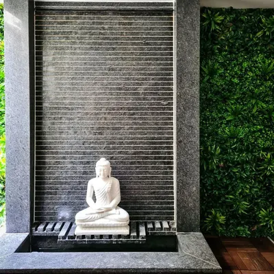 I designed this tranquil indoor water feature to be a peaceful retreat. It includes a white marble Buddha statue set against a dark, textured stone waterfall, flanked by a lush vertical green wall that brings nature indoors.