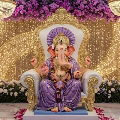 A truly regal setup for Ganesh Chaturthi, featuring the idol on an ornate throne. The backdrop is a curtain of golden lights, framed by columns of purple orchids and magnificent crystal chandeliers, creating a divine and luxurious atmosphere.