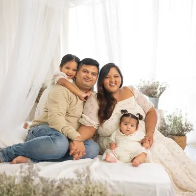 A full family portrait in my bright and airy studio. This setup features a comfortable bed, soft white fabrics, and delicate dried flowers for a warm, lifestyle feel.