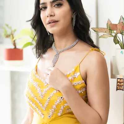 A close-up of the bright yellow Indo-Western outfit, focusing on the detailed embroidery on the bodice and the elegant diamond necklace.