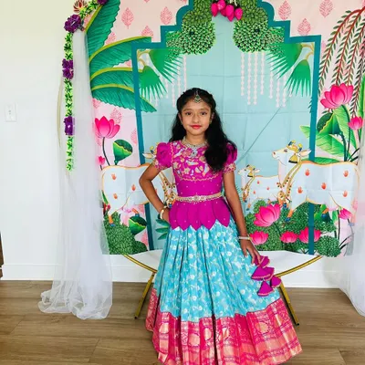 Our lovely client posing in her custom Banarasi pattu lehenga. The vibrant combination of a magenta peplum top and a turquoise brocade skirt looks stunning against the festive backdrop.