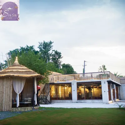 A beautiful daytime view of the property. This shot shows the lush lawn, a private bamboo cabana, and the indoor hall with its rooftop terrace, giving you a sense of the different spaces available.