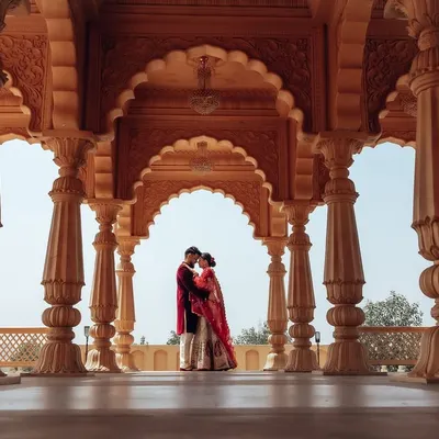 A classic, wide-angle shot capturing the scale of a royal courtyard. The symmetrical arches frame the couple perfectly, creating a powerful and majestic pre-wedding photograph.
