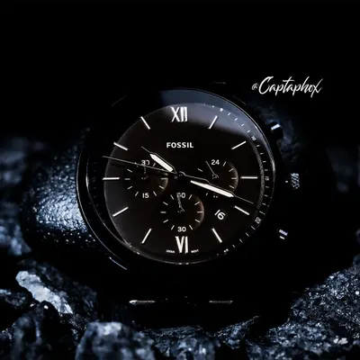 This is a dark and moody concept shoot for a Fossil watch. I placed the timepiece on textured, dark rocks to create a rugged, masculine aesthetic. The lighting is carefully controlled to catch the watch hands and markers, highlighting the fine details of the dial against the dark background.