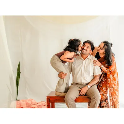 A heartwarming studio shot of a family, with the daughter planting a sweet kiss on her father's cheek. Our goal is to create a comfortable atmosphere where these loving, spontaneous moments can happen.
