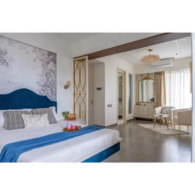 A wide view of a luxurious master bedroom, showing the sleeping area and a separate, cozy seating nook by the window. The design creates distinct zones for rest and relaxation within a single room.
