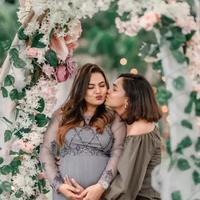 The joy of celebrating with loved ones. Here, the mom-to-be shares a sweet moment with a friend under a beautiful floral arch we created for her outdoor baby shower.