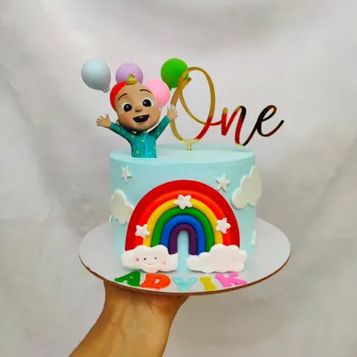 A cheerful Cocomelon cake for a first birthday. This design features a bright rainbow, fluffy clouds, and a JJ character topper, all on a sky-blue buttercream base.