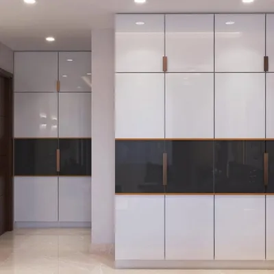 Sleek, high-gloss white wardrobes with minimalist handles and a contrasting dark accent panel, offering a modern and clean storage solution.