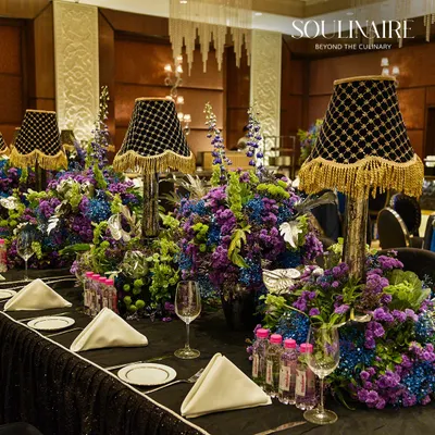 An exceptionally lavish tablescape featuring dramatic floral centerpieces with integrated lampshades. We curate perfect tablescapes that transform any social gathering into a timeless celebration of beauty and grace.