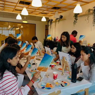 A corporate team fully engaged in a canvas painting workshop. Art is a fantastic way to encourage collaboration and creative thinking outside the office.