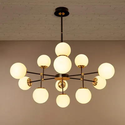 This multi-globe chandelier is designed to make a statement in a living room or over a dining table. The arrangement of opal glass globes on a black and gold frame provides ample, even lighting while adding a distinctly modern, architectural feel to the space.