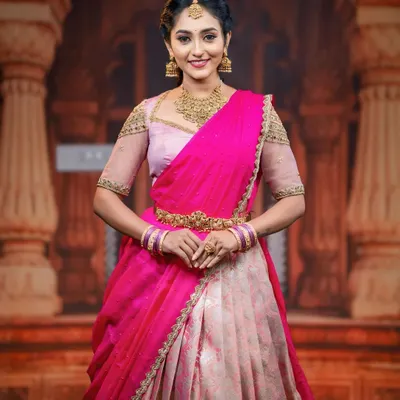 A model looking regal in a pink and cream half saree, paired with our classic matt gold finish choker, earrings, and maang tikka.
