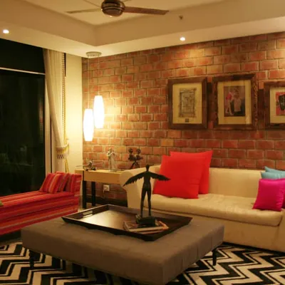 This living room is the perfect example of my design approach. I combined a bold, textured brick wall with a mix of contemporary and vintage furniture, like the striped chaise lounge and classic sofa. The vibrant cushions and graphic chevron rug bring an energetic yet cosy feel to the entire space, creating a home that is full of personality.