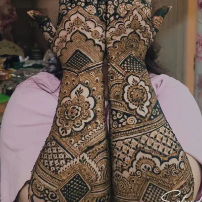A gorgeous, full-coverage design for the bride's mom. This intricate henna features geometric grids, floral mandalas, and detailed finger work, covering the hands and forearms completely.