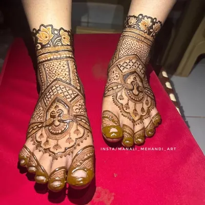 A close-up of a bridal foot mehandi design. The pattern covers the entire foot with a mix of traditional motifs and fine line work, ending with a floral cuff.